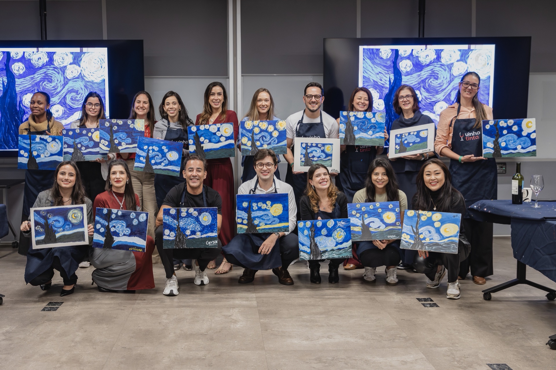 Participantes do RHZ Experience Vinho & Tinta segurando suas pinturas da Noite Estrelada